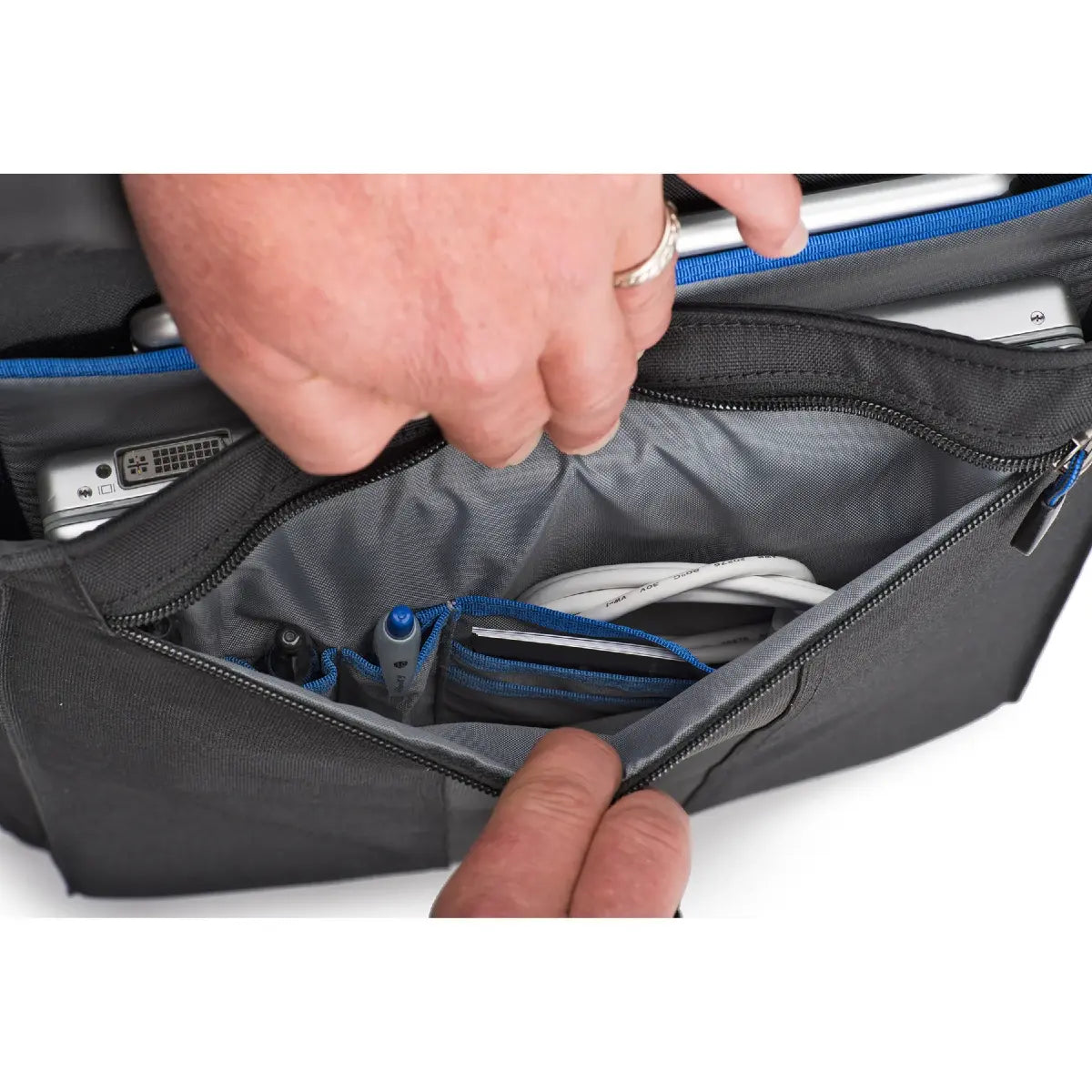 Person opening a black bag with electronic devices inside on a white background