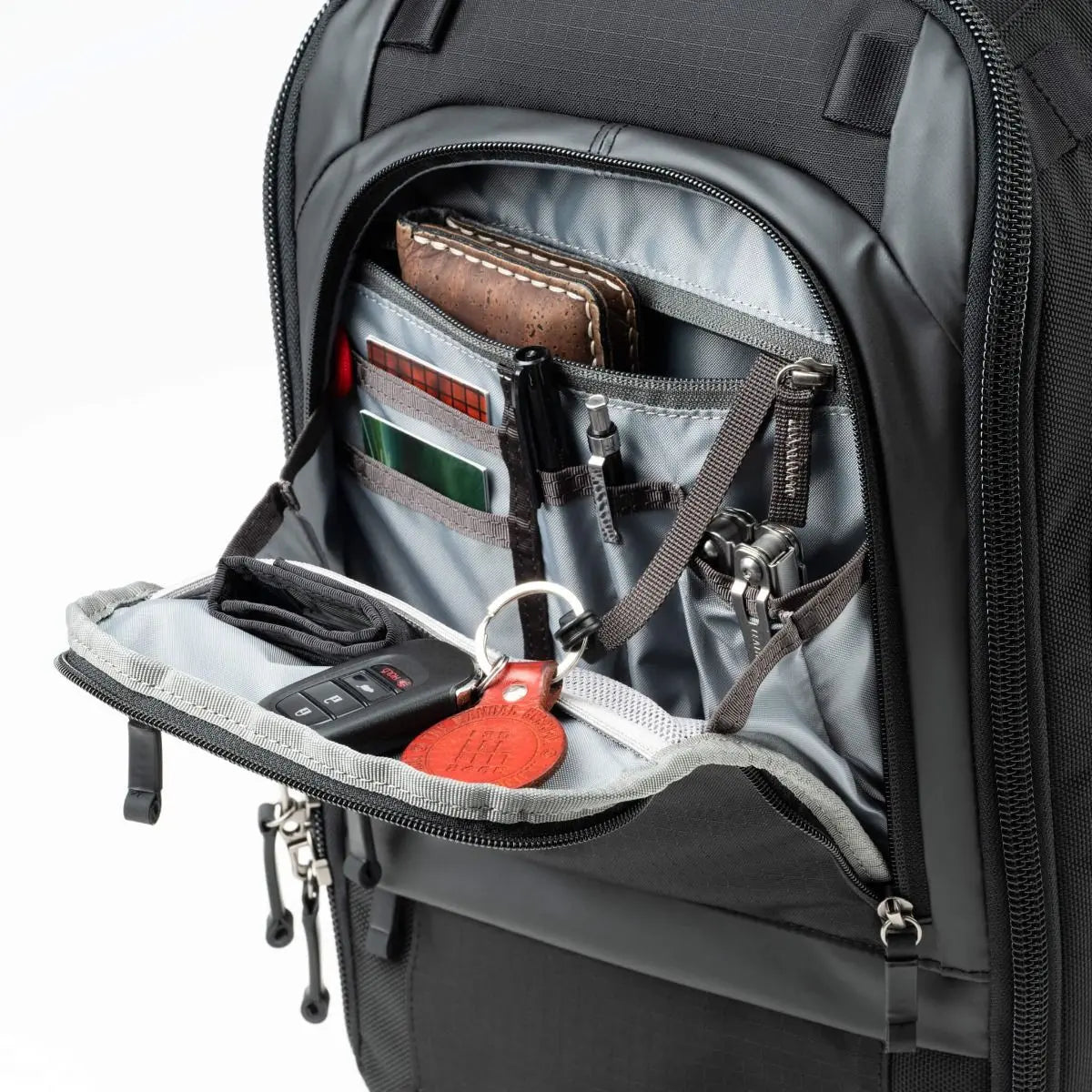 Open backpack showing organized compartments with items like a phone, wallet, and keys.