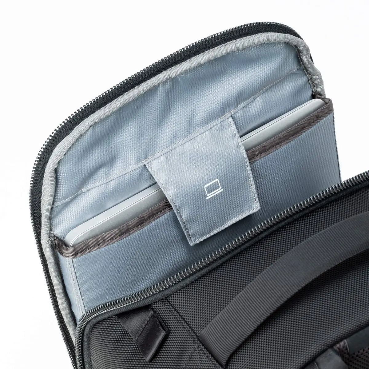 Open black backpack with gray interior showing a compartment with a logo tag.