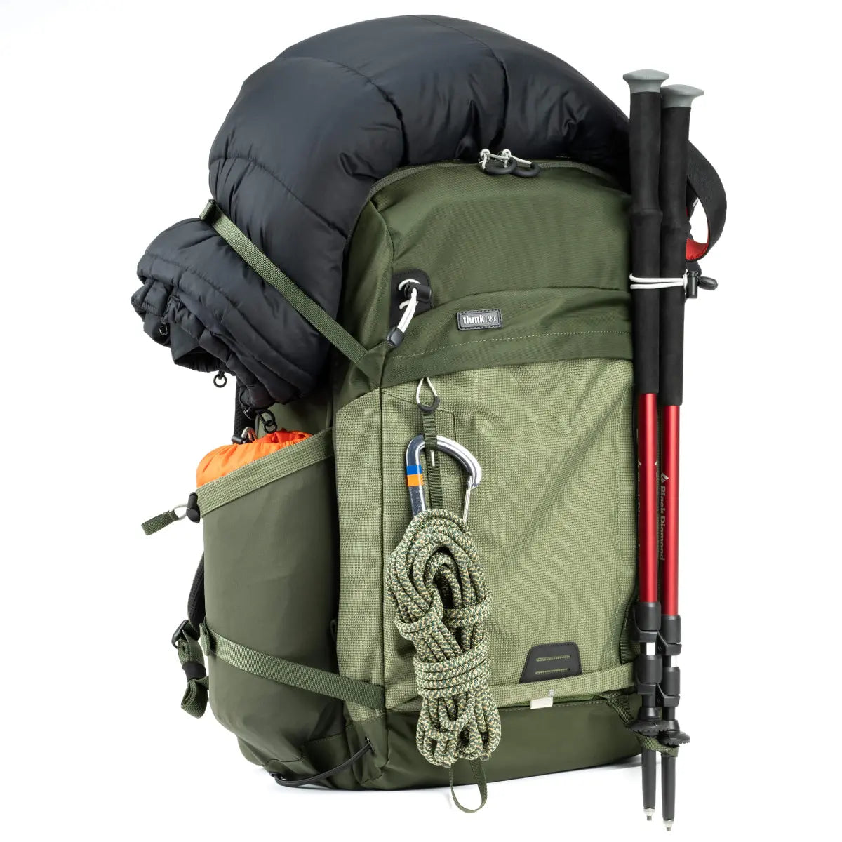 Green hiking backpack with black cover, trekking poles, and rope on a white background