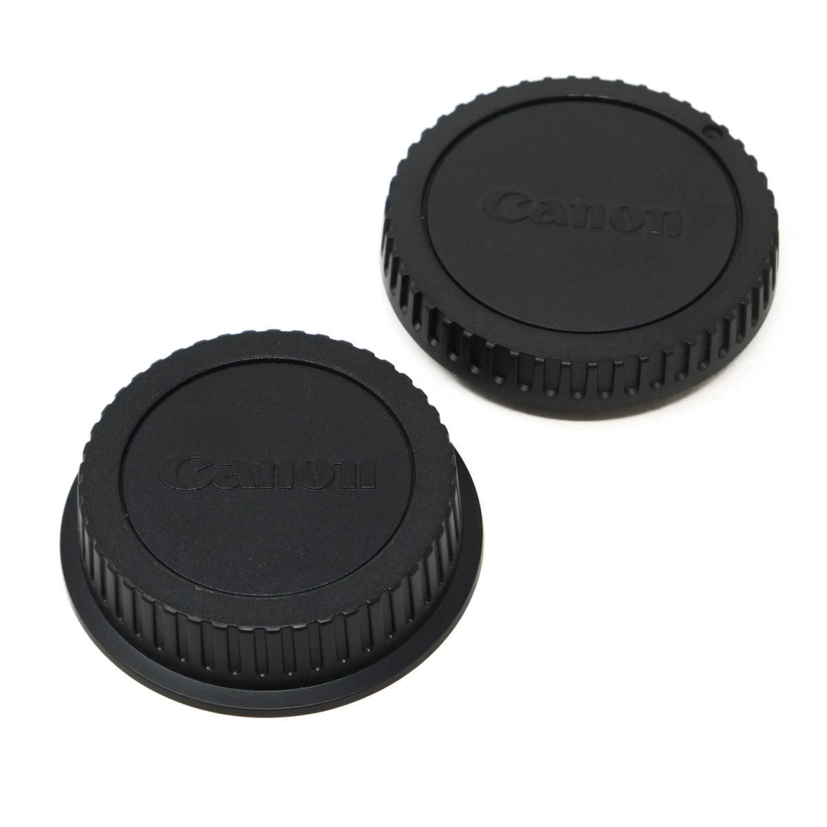 Two black Canon lens caps on a white background