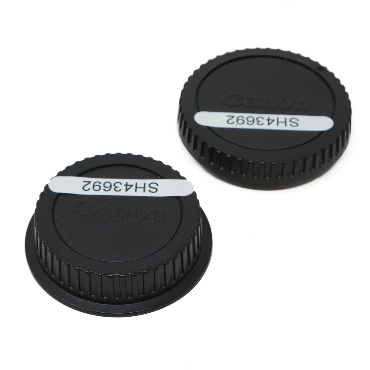 Two black Canon lens caps on a white background