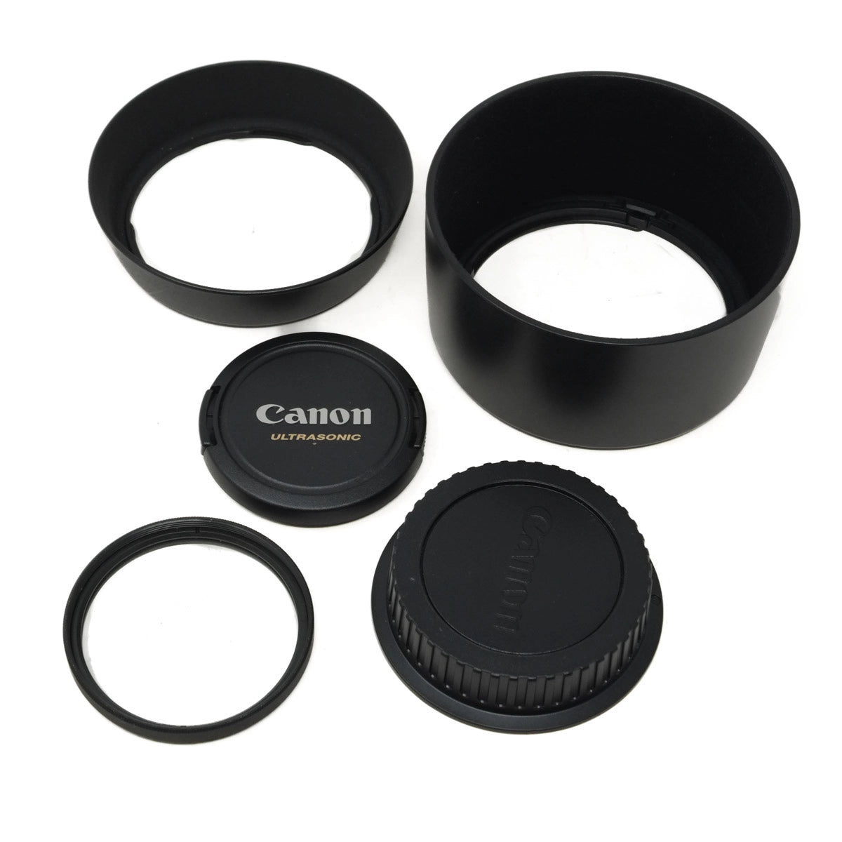 Canon lens accessories including a lens hood, lens cap, and front and rear covers on a white background.