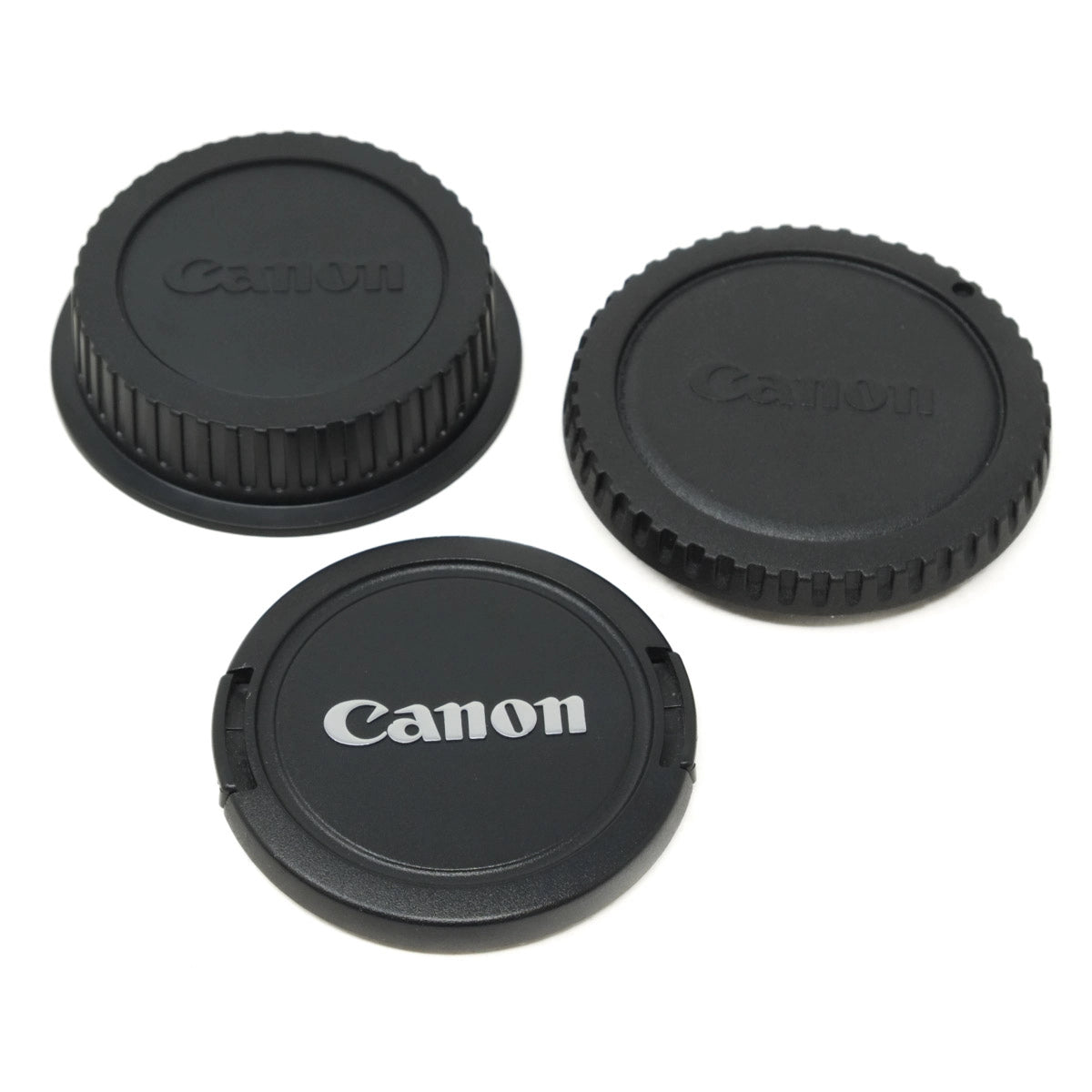 Three Canon lens caps on a white background