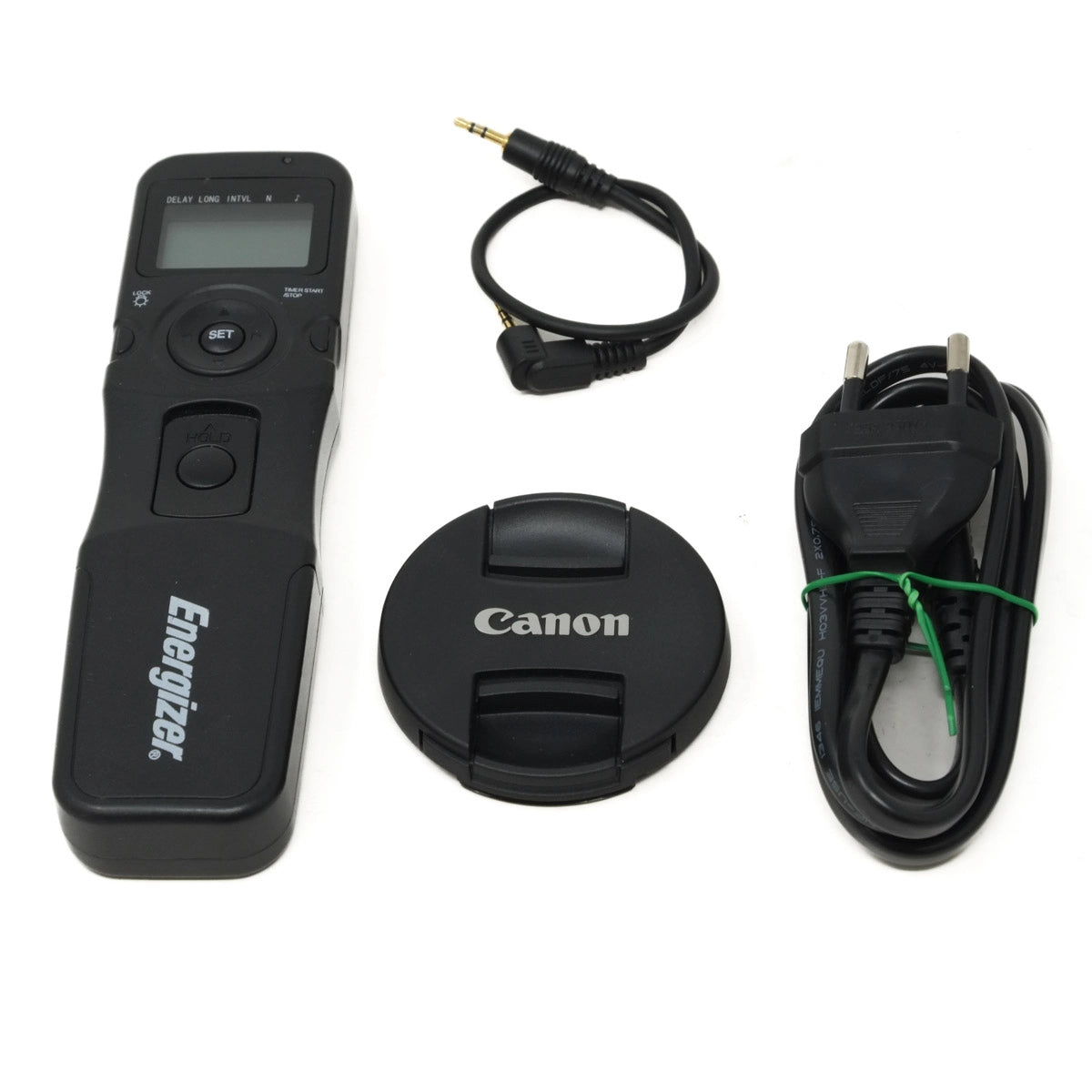 Camera remote control, lens cap, and power adapter on a white background