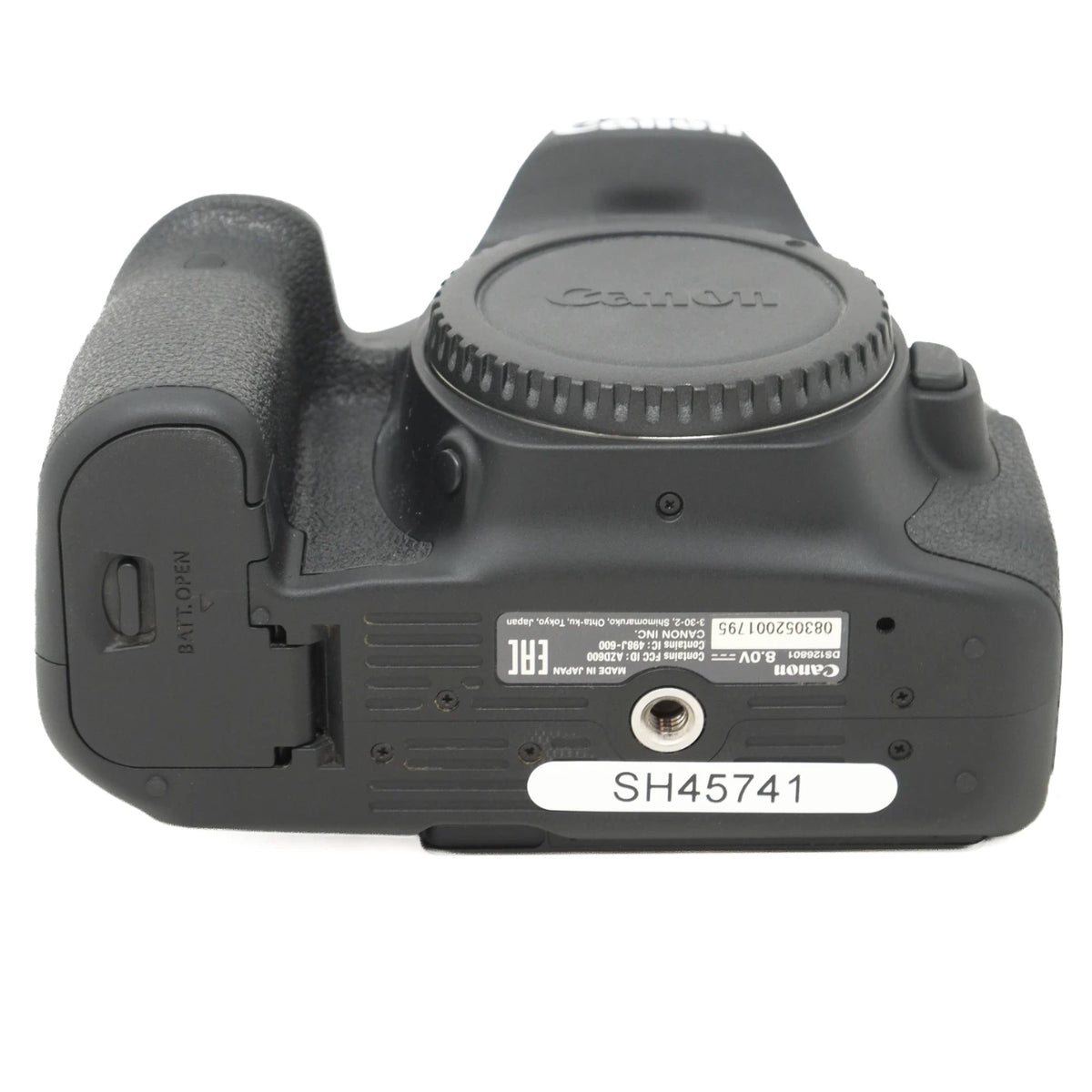 Canon DSLR camera body rear view showing the battery compartment cover open, with the lens cap removed, control buttons on top on a white background.