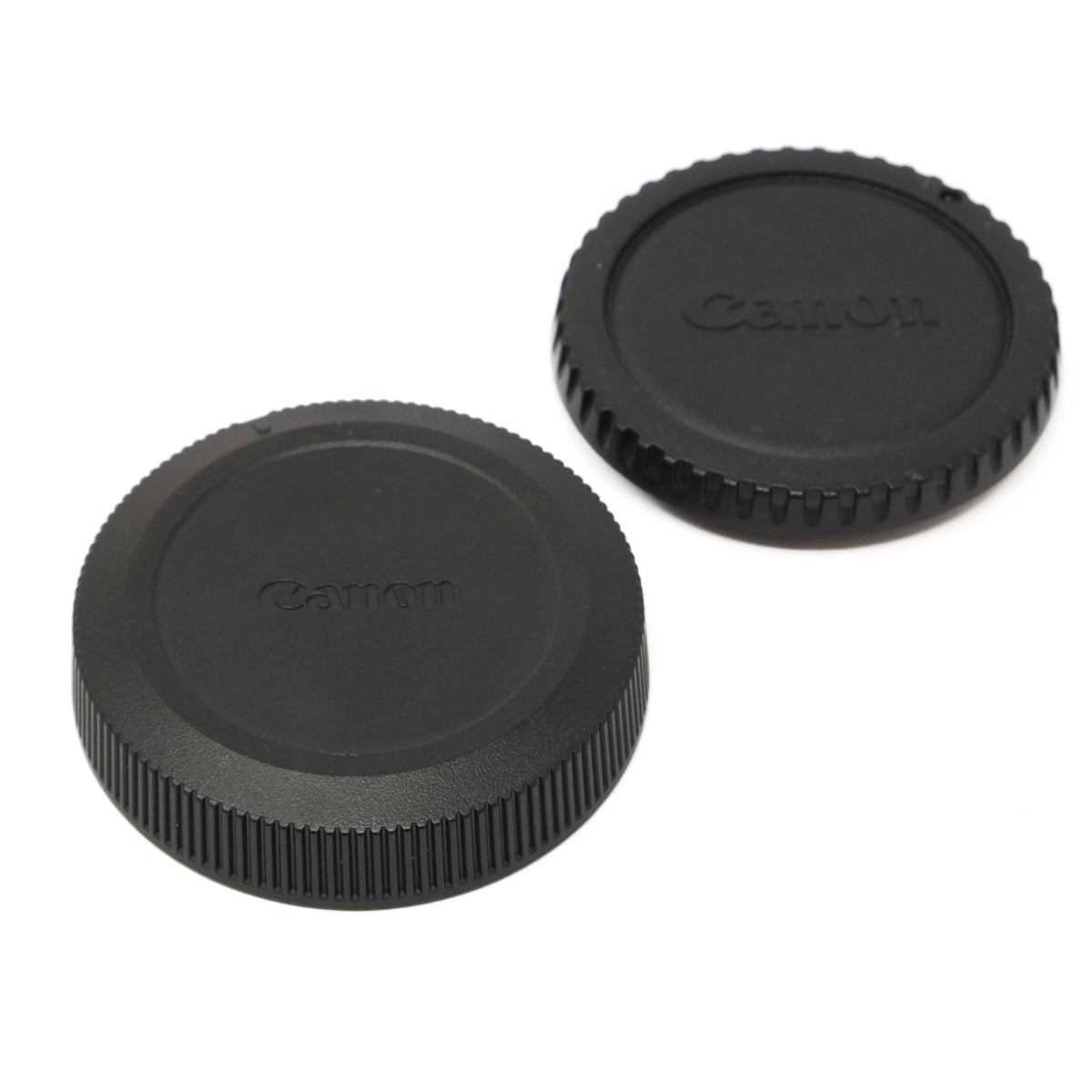 Two black Canon lens caps on a white background