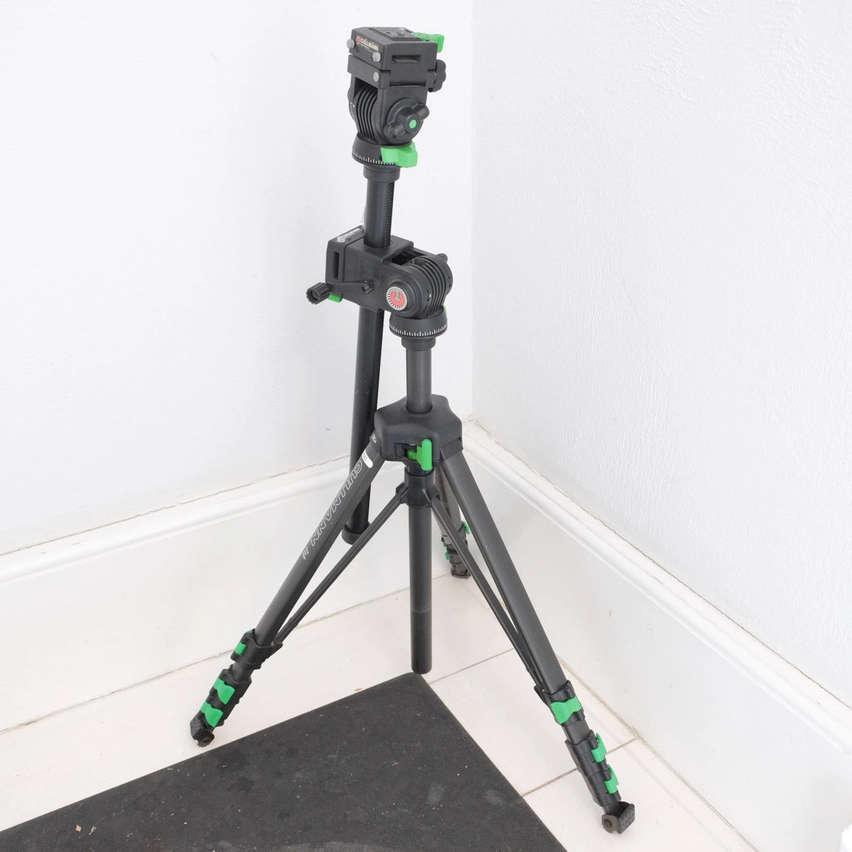 Camera tripod with head on a white floor corner