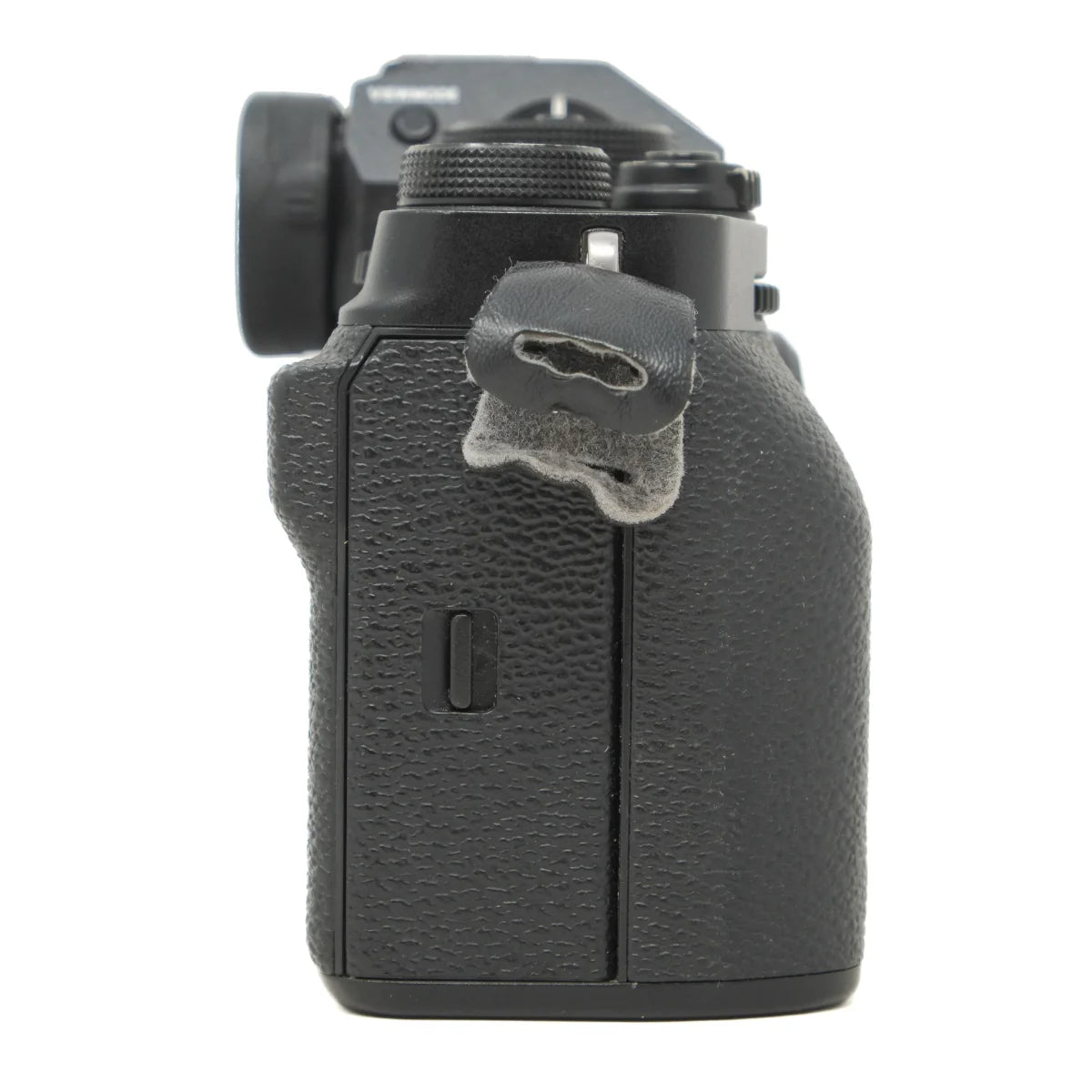 A close-up side view of a black textured camera body, likely a mirrorless camera, showing the grip, dial, and hot shoe attachment on a plain white background.
