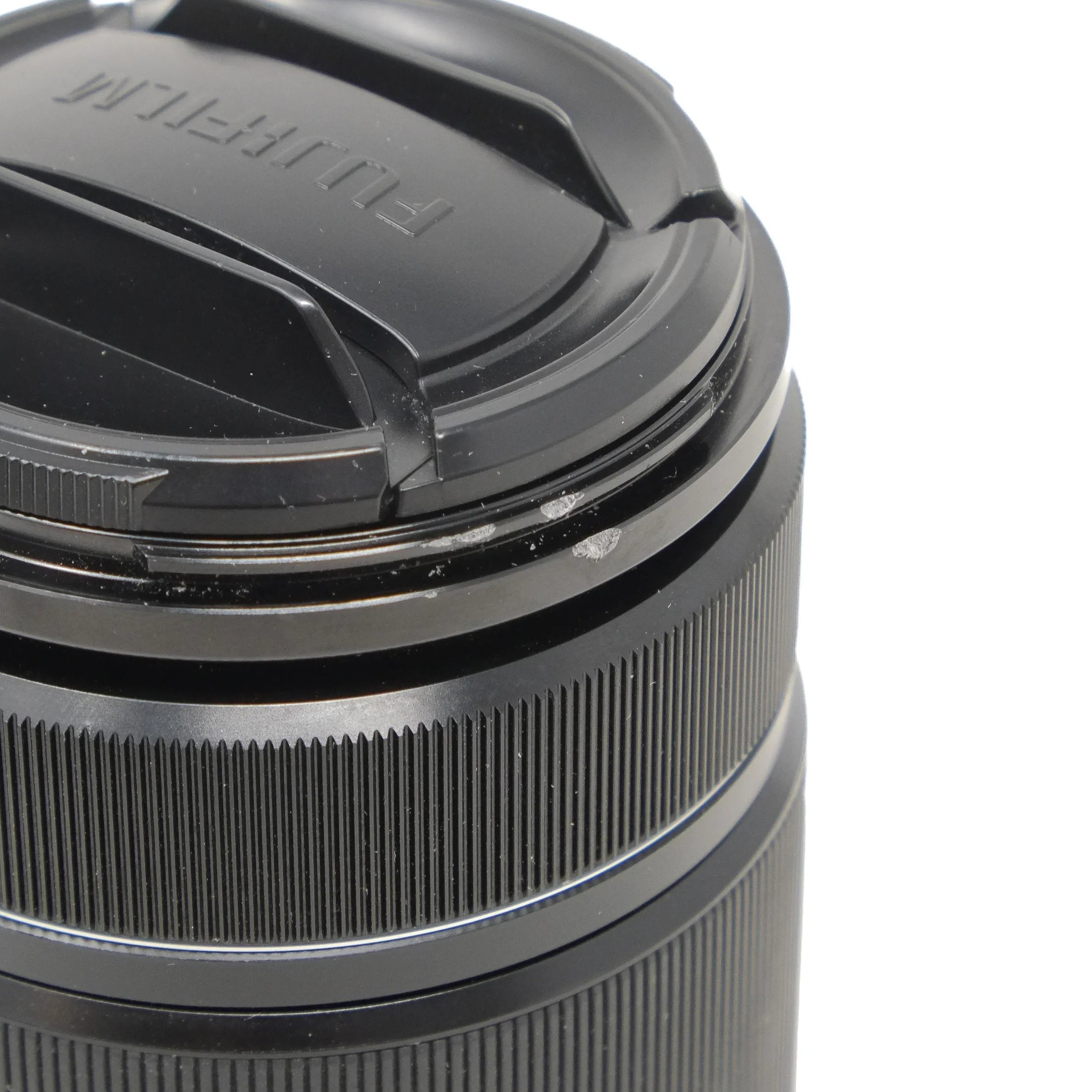 Camera lens with a lens cap on a white background