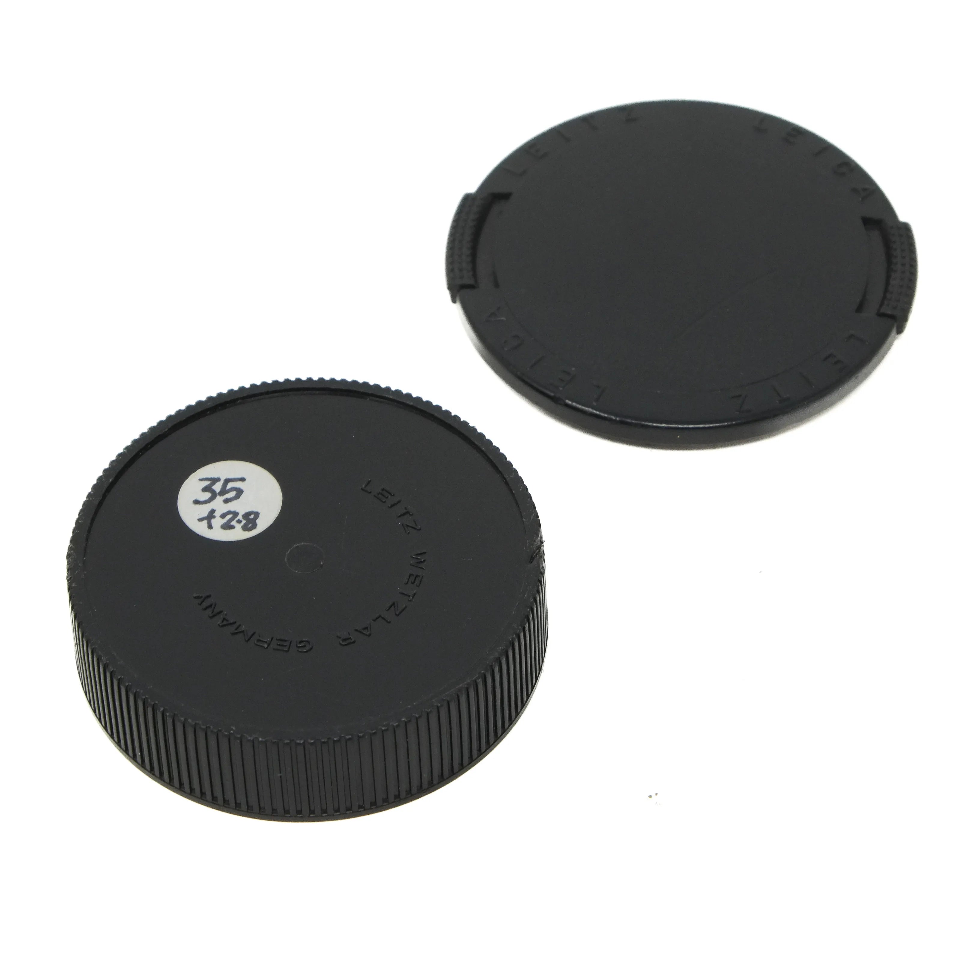 Two black camera lens caps on a white background