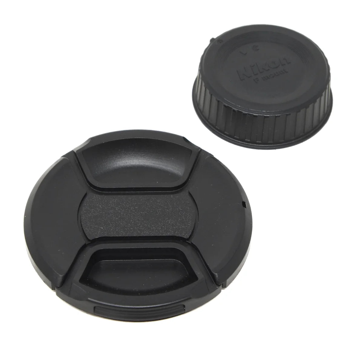 Two black plastic camera lens caps shown on a plain white background, with one cap open in the foreground and one closed cap showing the embossed Nikon logo in the background.