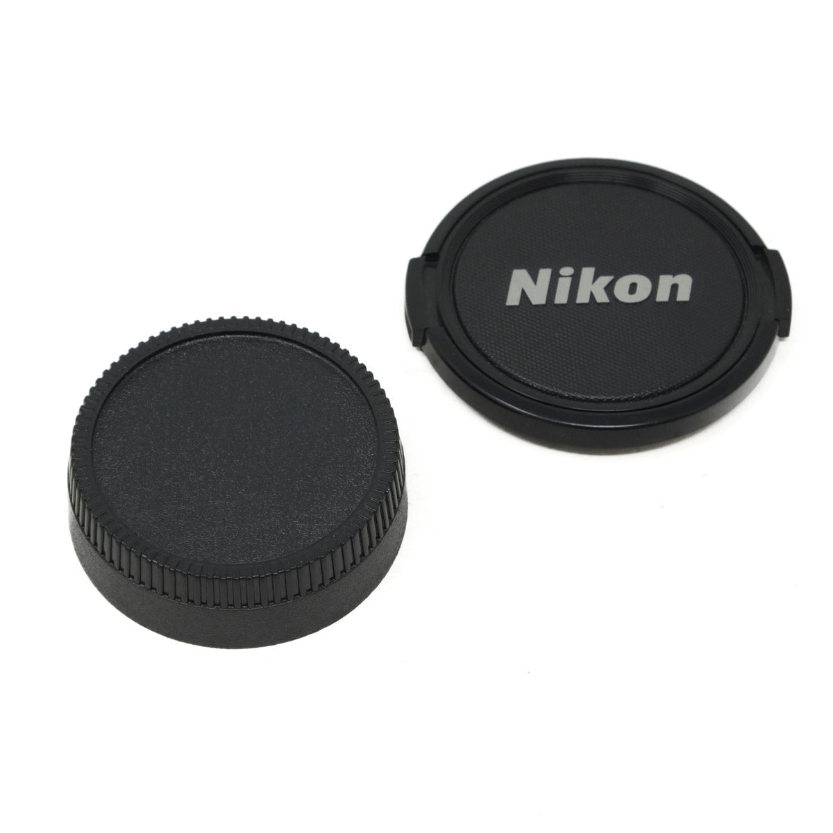 Two camera lens caps, one with Nikon logo, on a white background