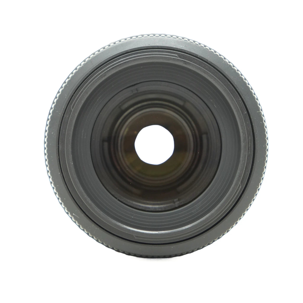 A close-up, front-facing view of a camera lens with a textured outer ring, dark gray metal barrel, and a circular glass center, isolated on a white background.
