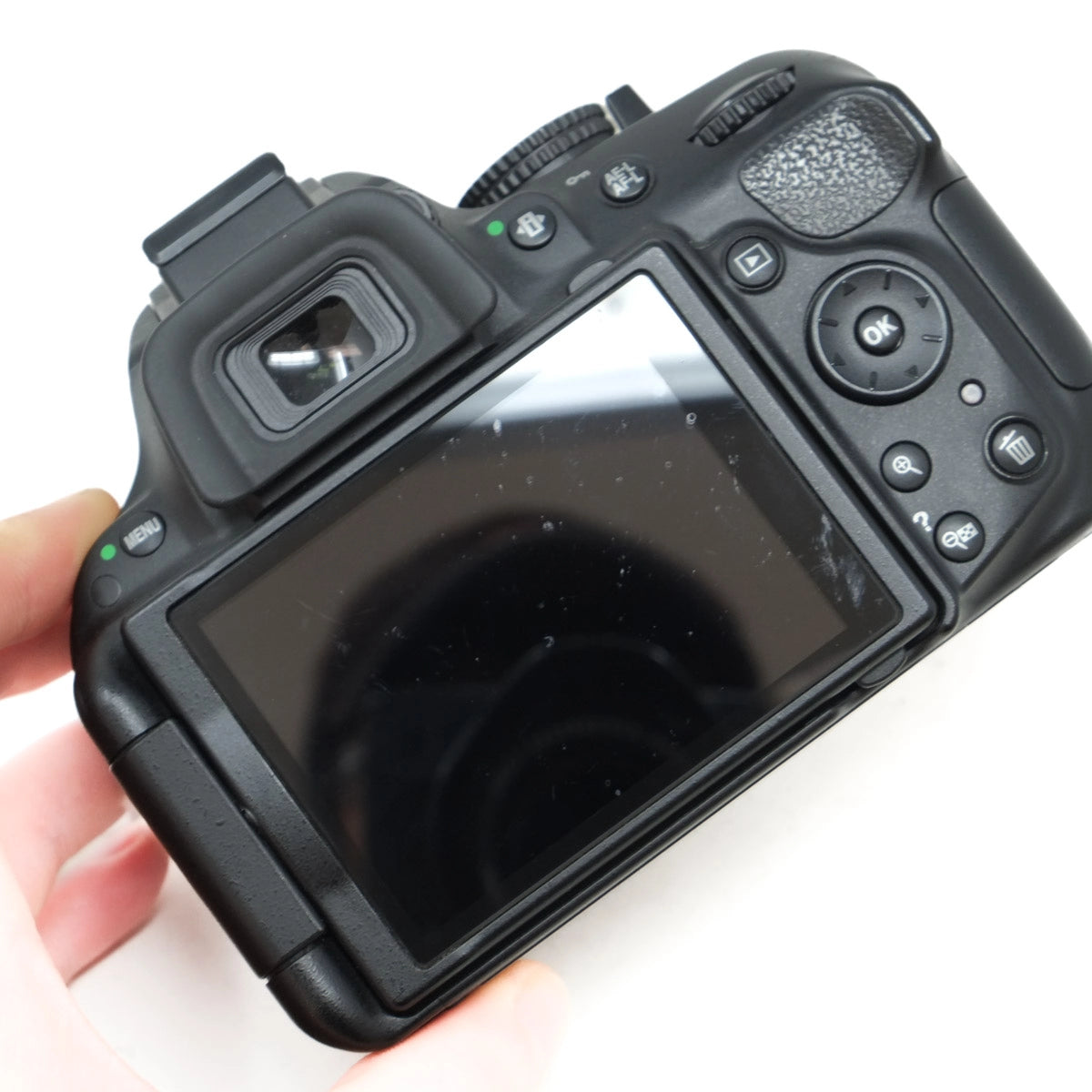 Black camera back with screen held by a hand on a white background