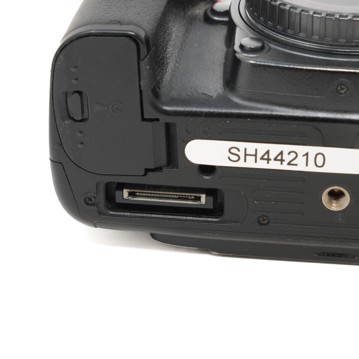 Close-up of a camera body with a label 'SH44210' on a white background