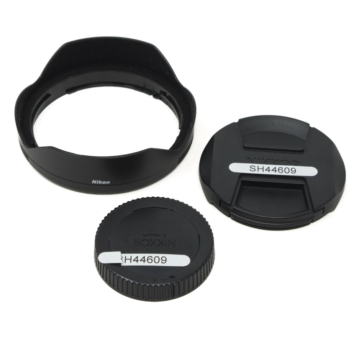 Canon camera lens accessories including a lens hood, front cap, and rear cap on a white background.