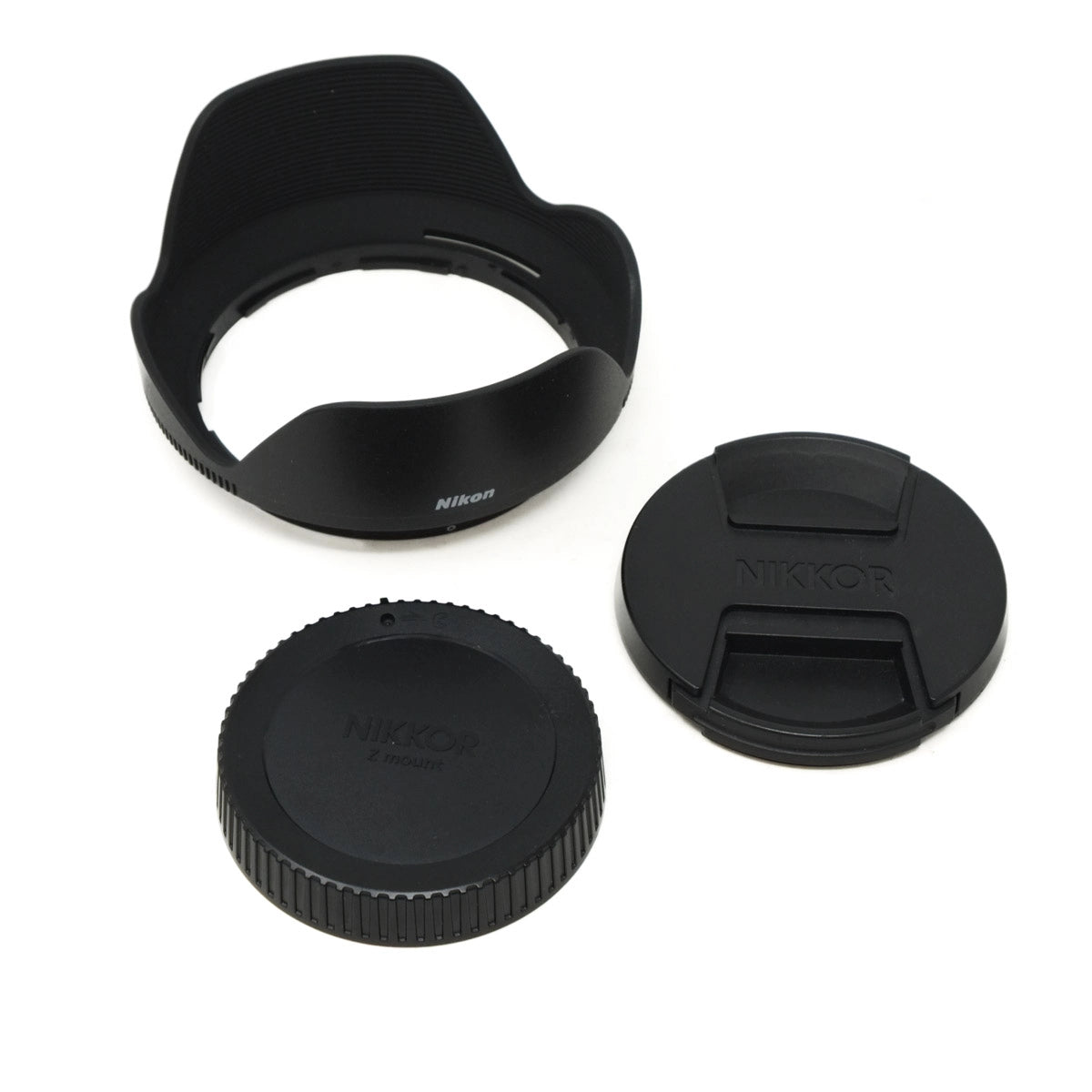 Nikon lens accessories including a lens hood, front cap, and body cap on a white background.