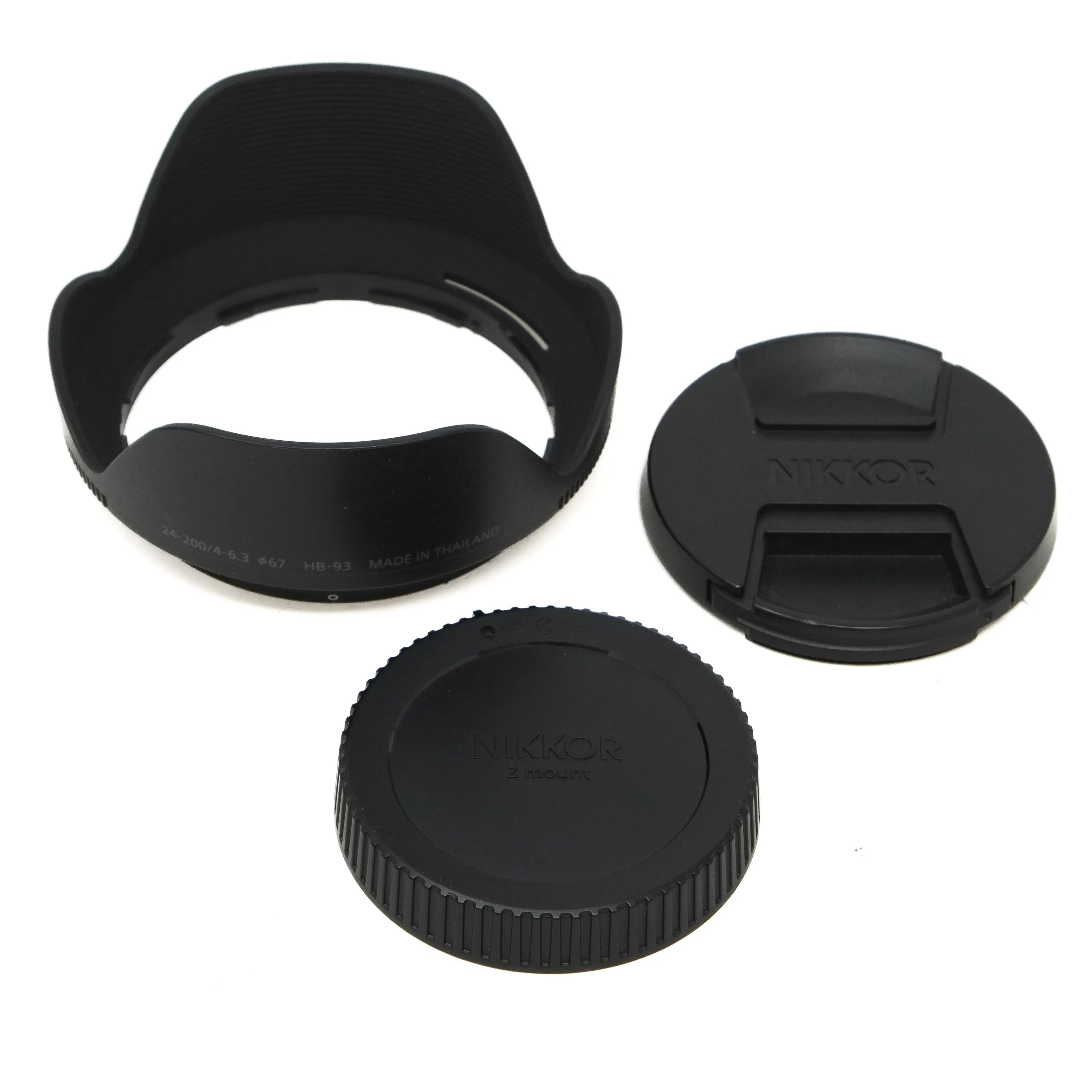 Camera lens accessories including a lens hood, front cap, and rear cap on a white background