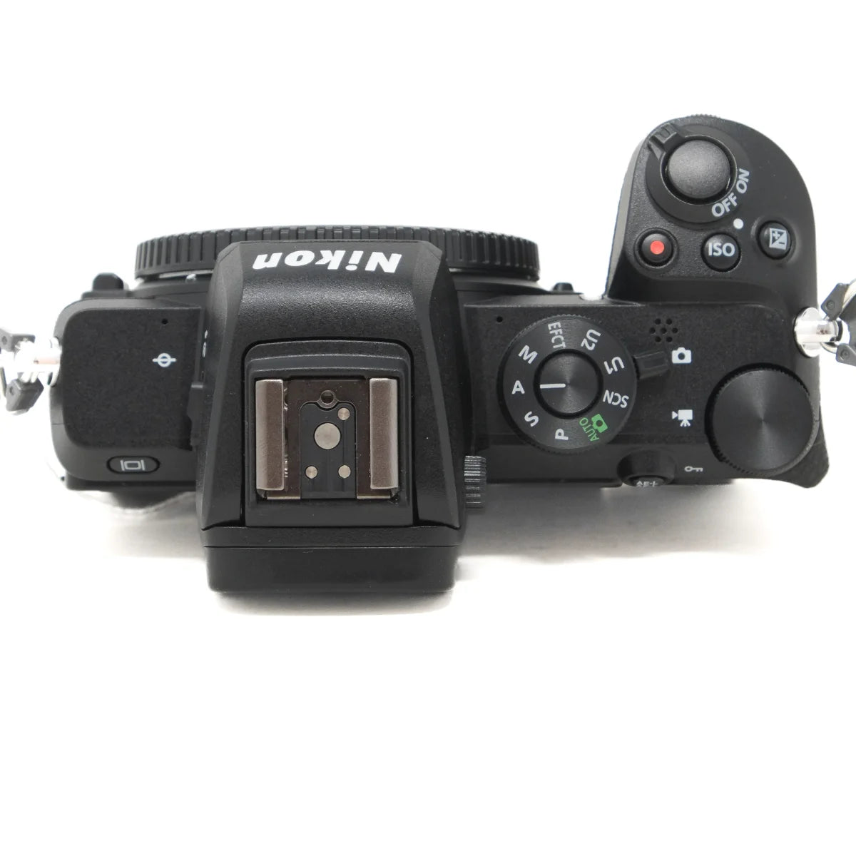 Top-down view of a black Nikon mirrorless camera body with mode dial, shutter button, hot shoe, and control buttons visible on a white background.