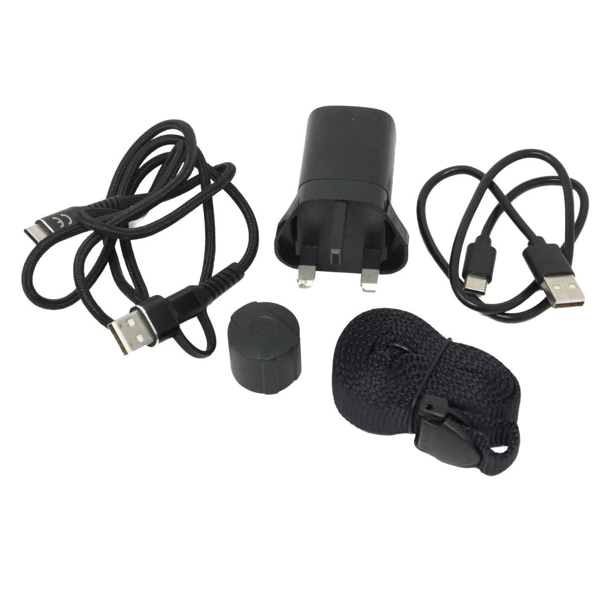 Black USB charging accessory kit on a white background, including a UK two-pin wall charger, two USB-C to USB-A cables, a small round black cap, and a black woven strap with a plastic buckle.