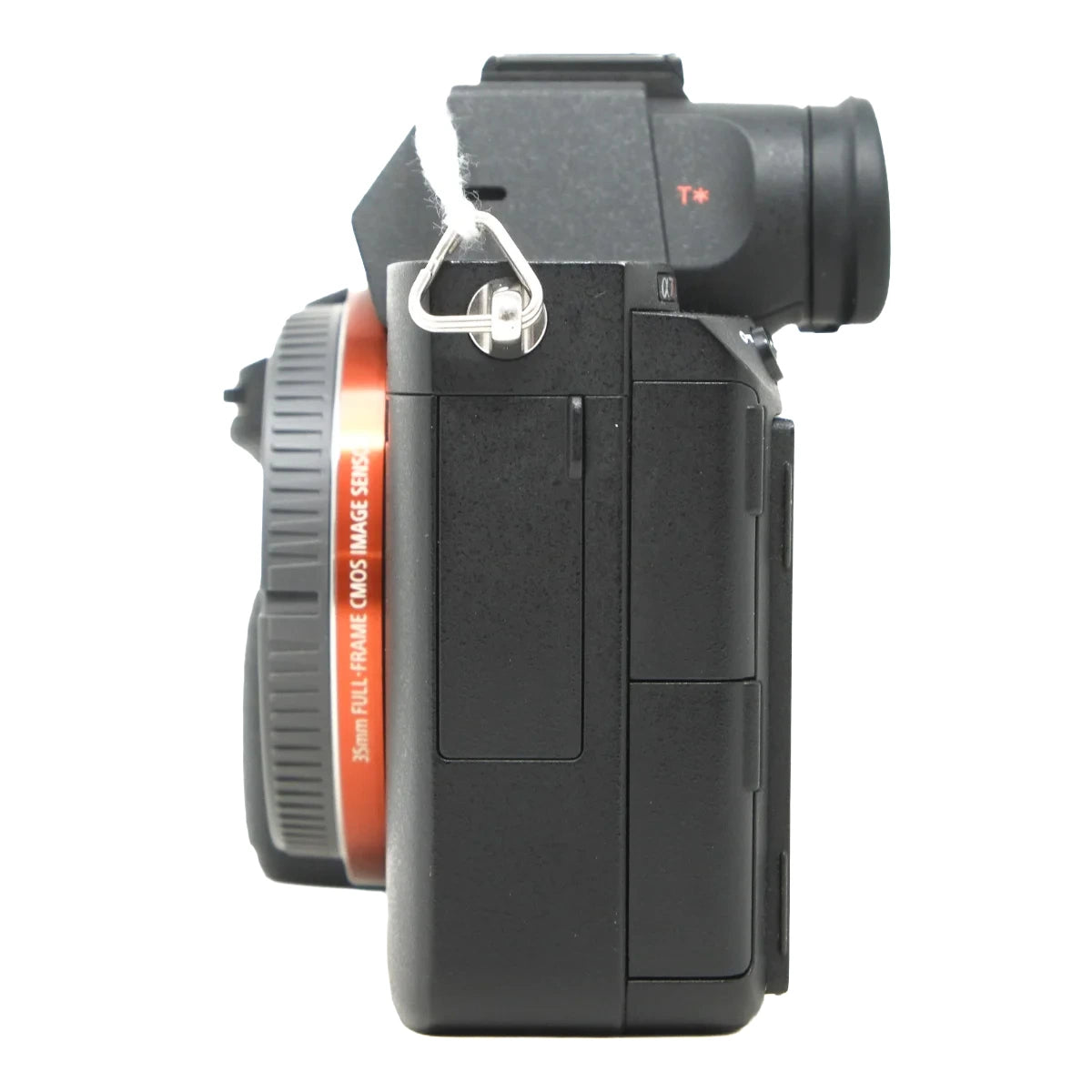 A black mirrorless camera body with an attached lens, shown from a side profile view against a solid white background. The camera body is matte black with a small red 'T+' marking, and the lens has a distinctive orange ring with white text.