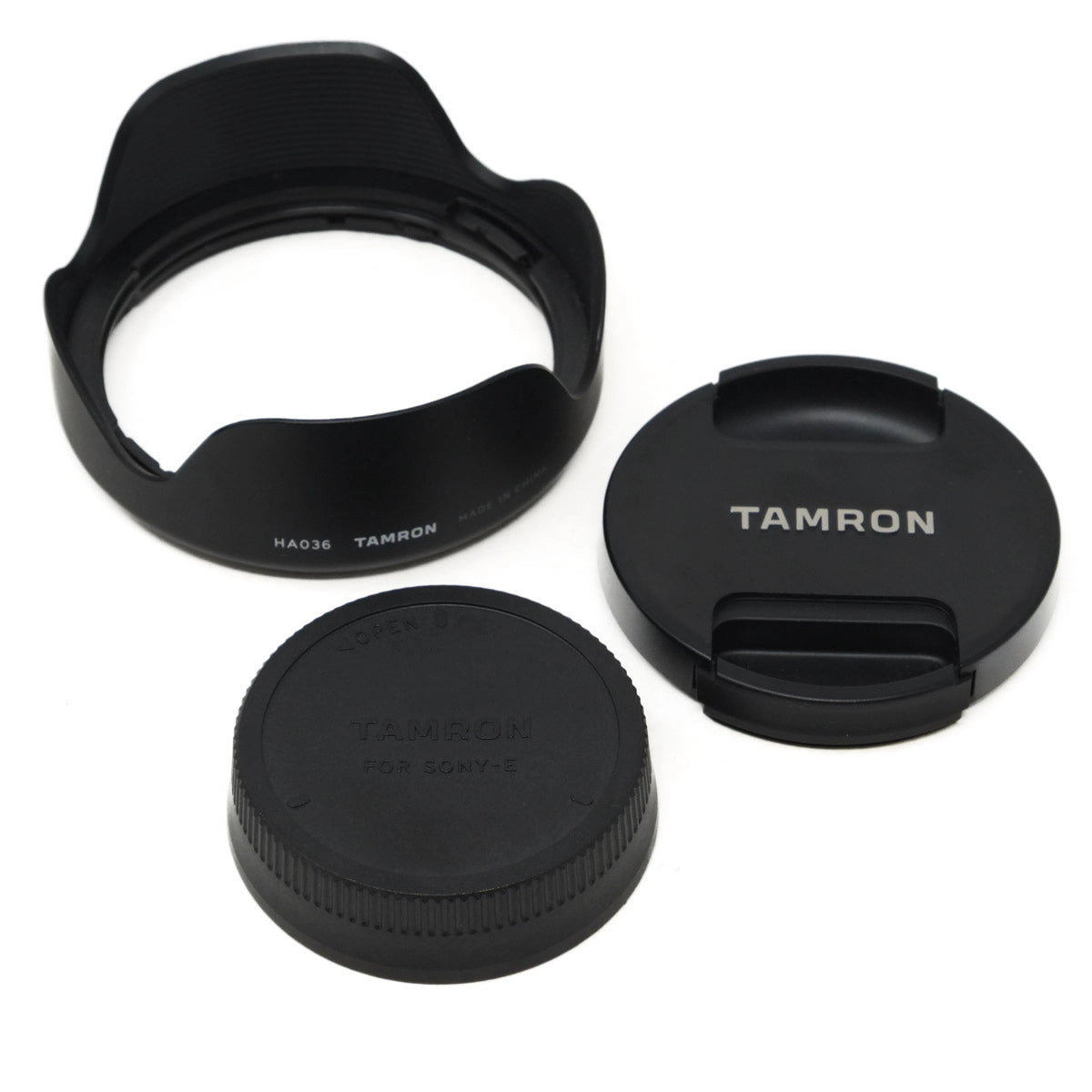 Three black camera lens caps with 'Tamron' branding on a white background