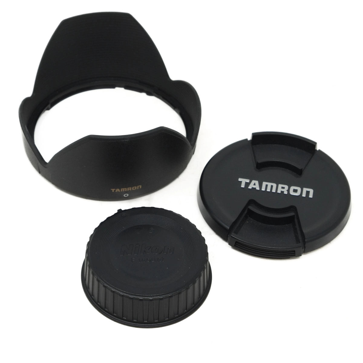Three black camera lens caps with 'Tamron' branding on a white background