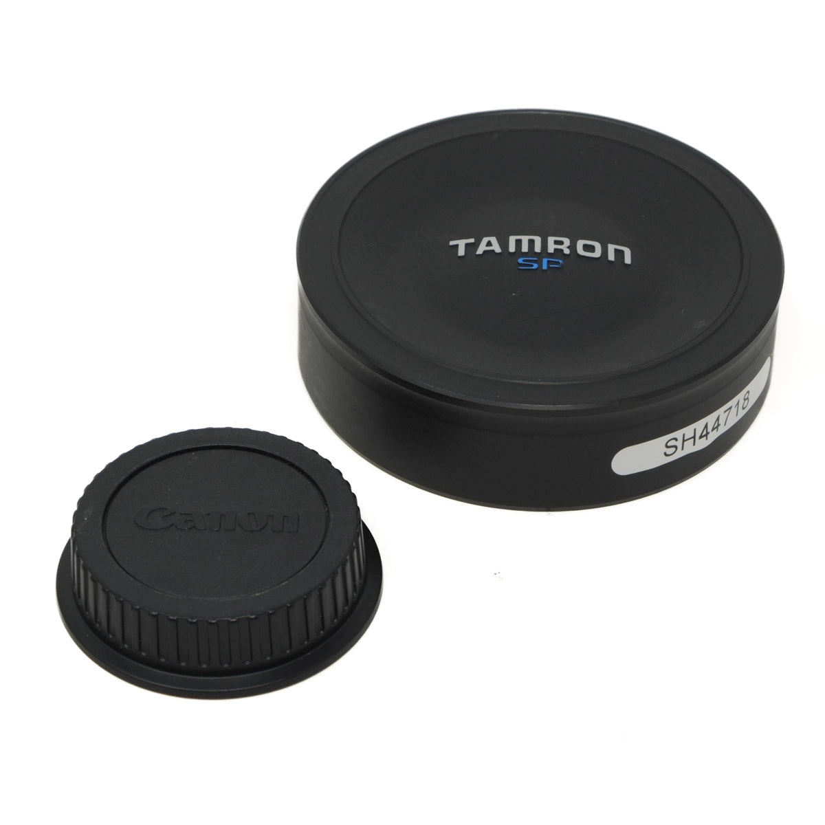 Two camera lens caps, one with Canon logo and the other with Tamron logo, on a white background.