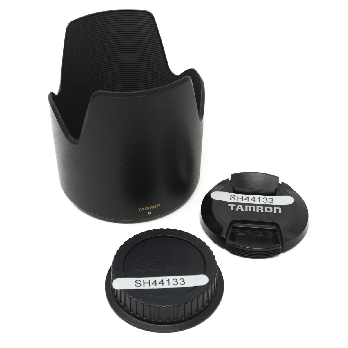 Set of Tamron camera lens accessories including a lens hood and two lens caps on a white background.