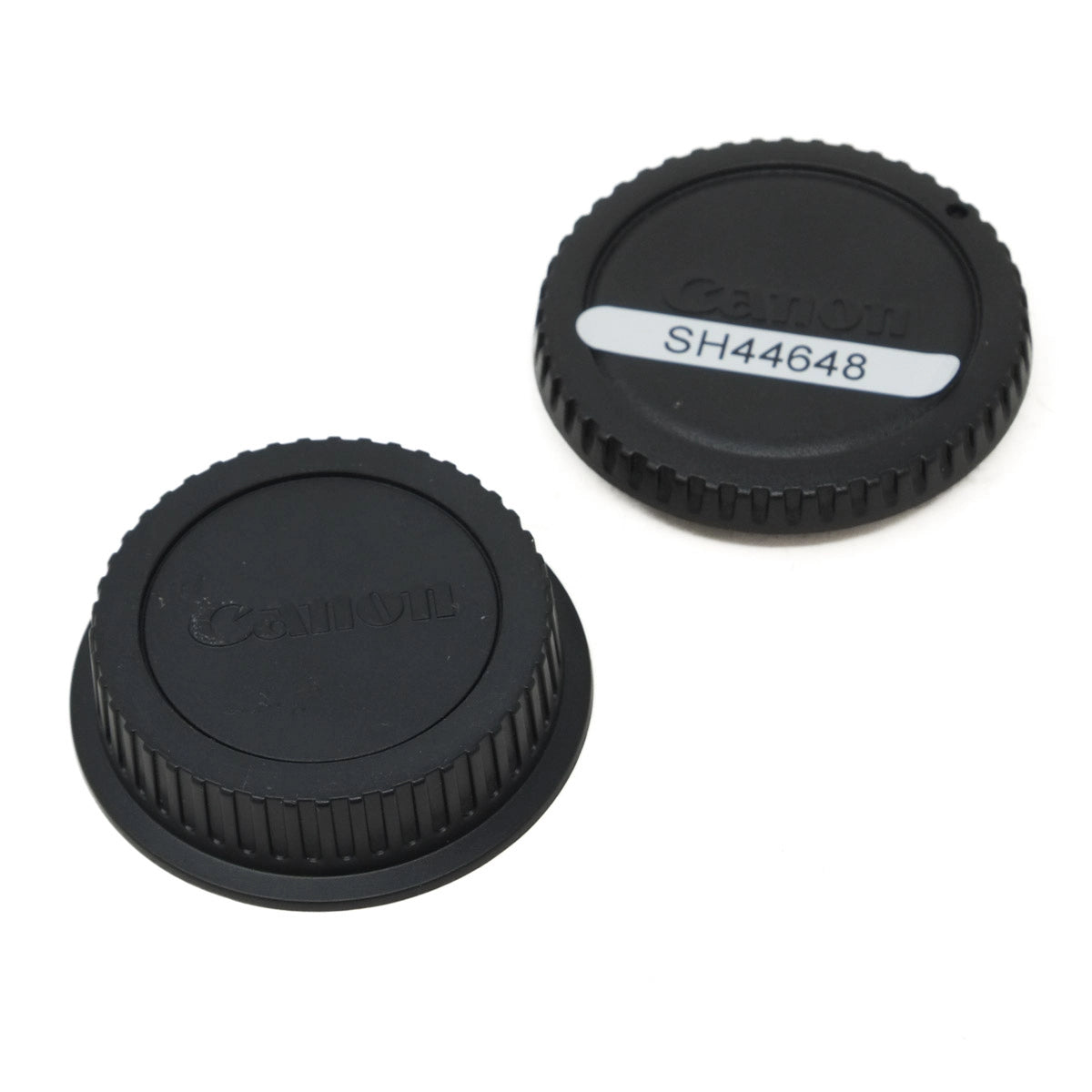 Two black Canon lens caps on a white background