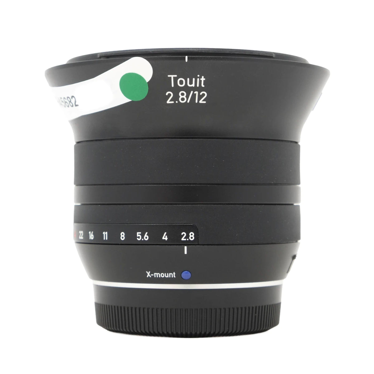 A black Zeiss Touit 2.8/12mm f/2.8 X-mount lens with a white and green focus switch, shown on a clean white background.