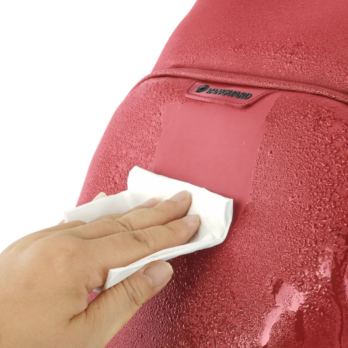 Person cleaning a red backpack with a white cloth on a white background