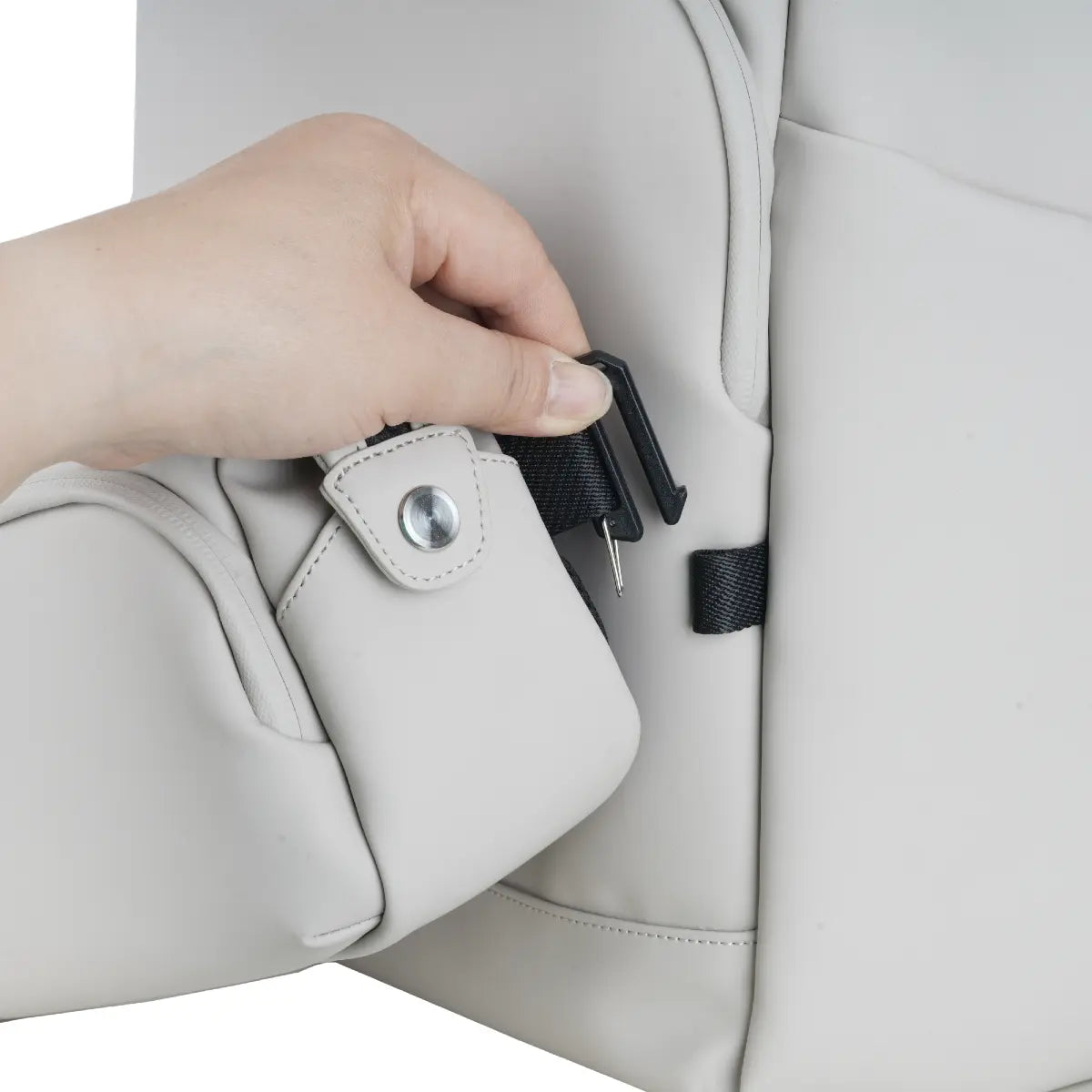 Hand adjusting a black strap on a beige car seat.