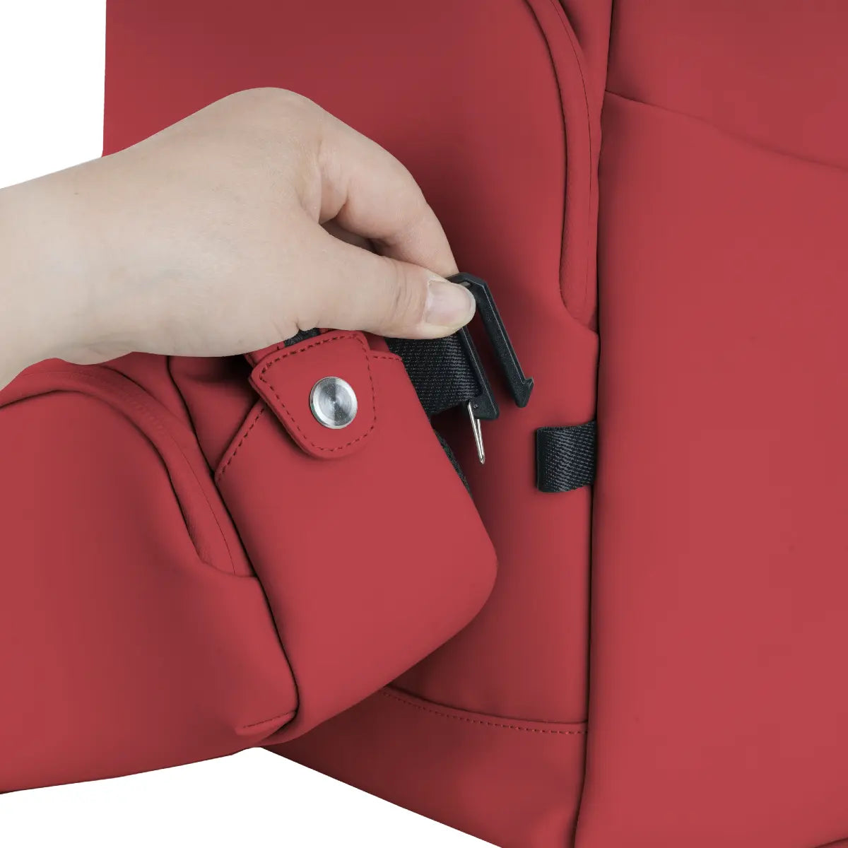 Red backpack with a hand adjusting a black strap on a white background