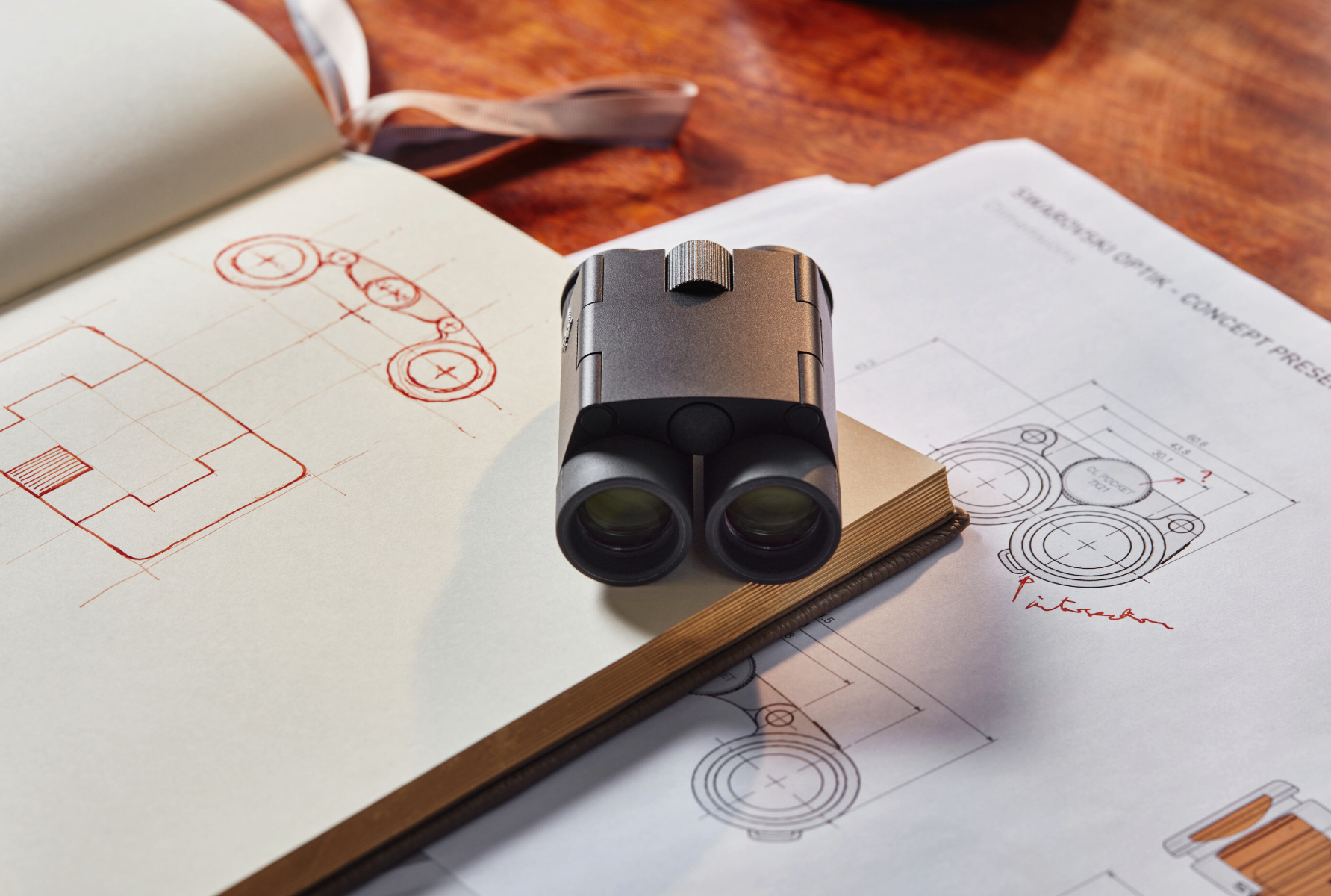 Swarovski 7x21 CL Curio compact binoculars - Black - Product Photo 5 - Front view of the binoculars folded whilst resting on a diagram sketched onto a paper notebook to show the scale